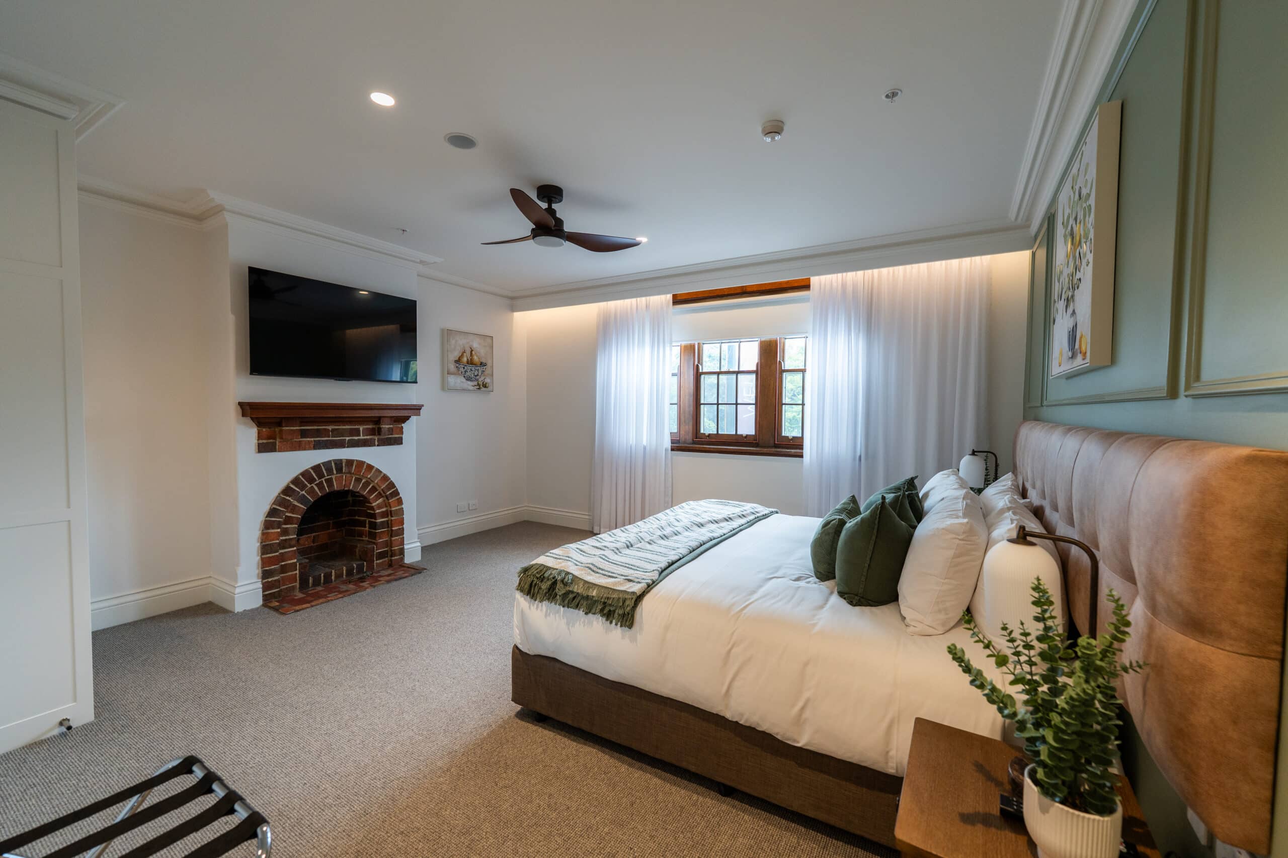 Wider room view showing how the curtains balance the window, bed and fireplace.