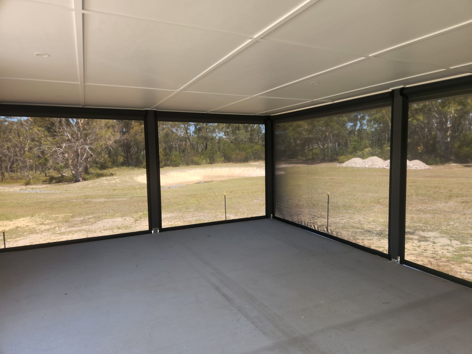 Interior view of a Wollongong alfresco area enclosed with Ziptrak awnings, showing filtered outdoor views through the fabric.