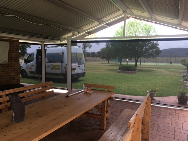 Dark Ziptrak outdoor blind fitted across a covered patio opening in Greater New England by Apollo Blinds