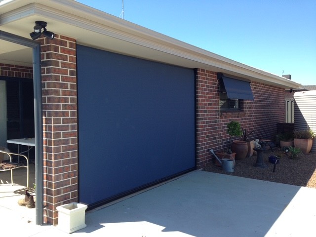 Dark outdoor blinds and a matching awning installed on a brick home by Apollo Blinds Tamworth.